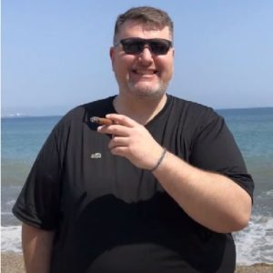 Bryan holds a cigar and smiles at the camera before weight loss